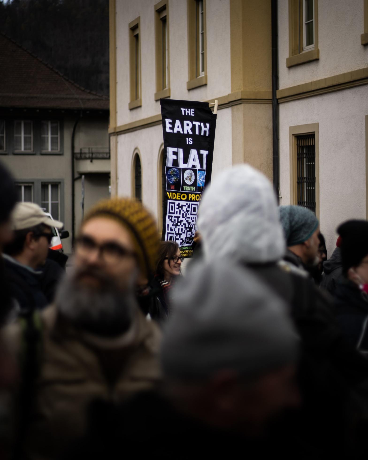 image of a crowd of people (blurred) with a banner behind them with the words, the earth is flat