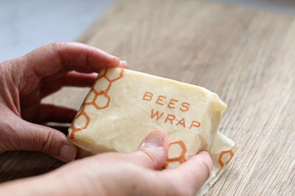 image of a woman holding a soap covered in a beeswax wrap that has the text "bees wrap" on it